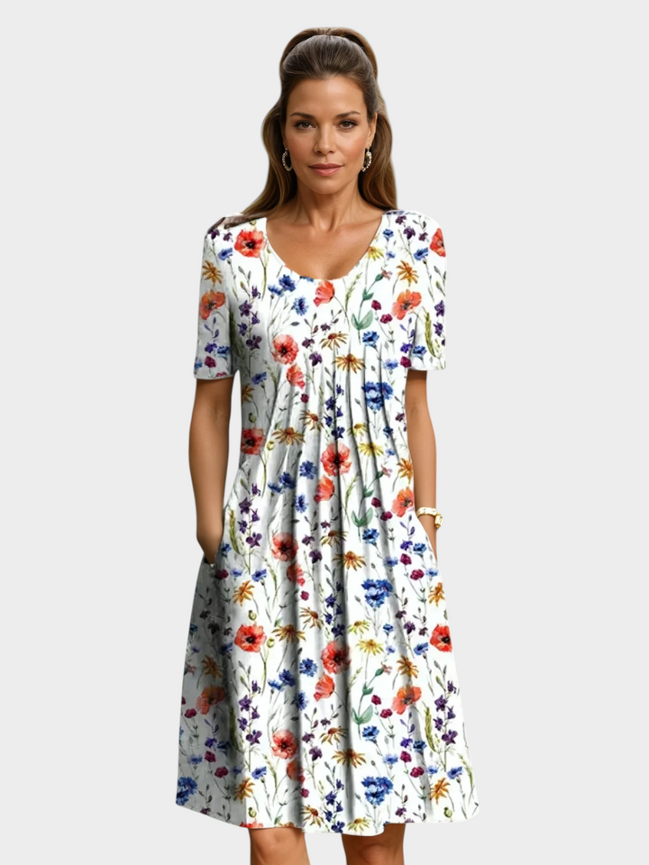 Aurore Paris midi dress featuring a white base with a colorful floral print, round neckline, and side pockets.