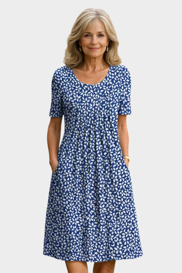Aurore Paris Violette midi dress in blue with a white floral pattern, featuring a round neck and side pockets.